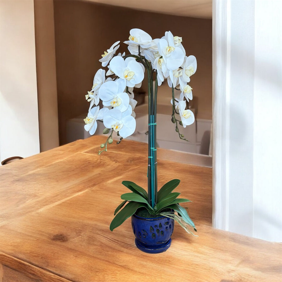 Artificial orchid flowers in a blue ceramic pot for elegant indoor spaces
