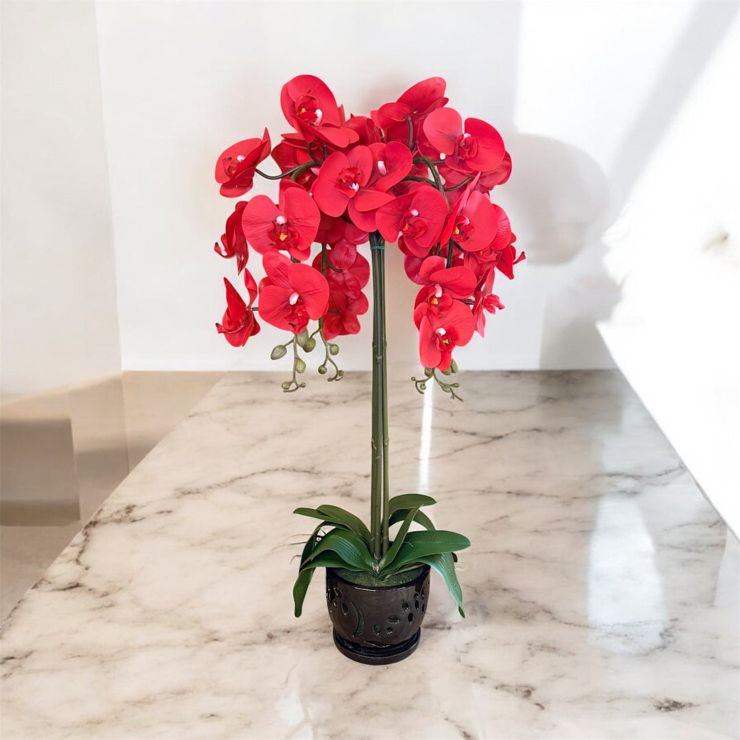 Artificial red orchid plant featuring vibrant red flowers in a decorative pot