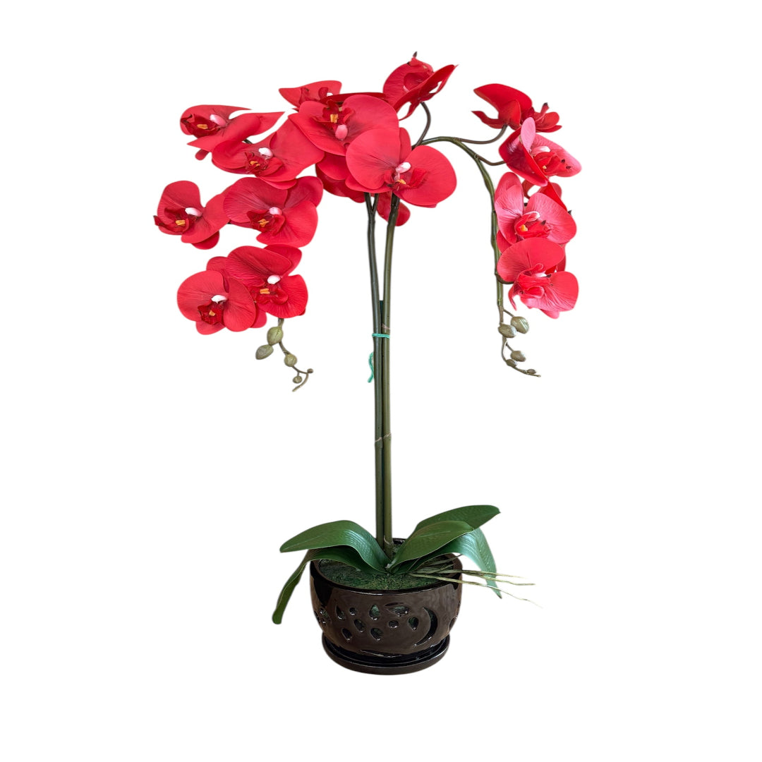 Realistic artificial red orchid flowers arranged in a sleek black ceramic planter